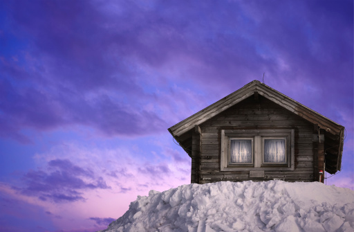 Idyllic winter scene with wooden hut on large pile of snow...