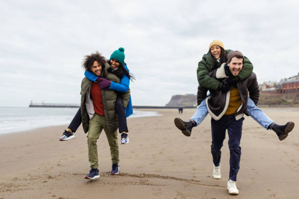 istock Couples Piggybacking along the Beach 1706188248