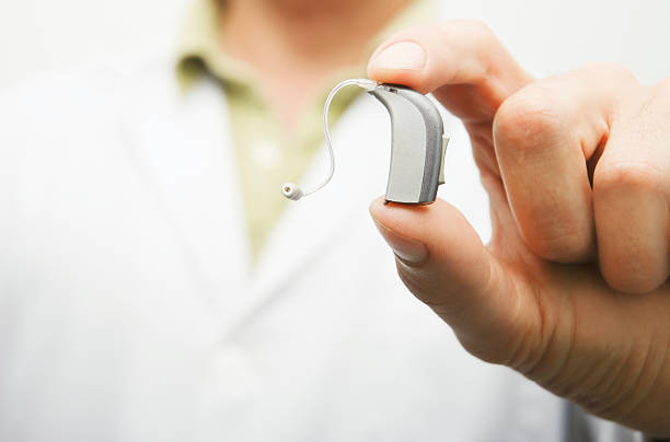 Hearing aid Doctor shows a last generation hearing aid device.More hearing and Ear health related files at: Doctor showing hearing aid stock photo stock pictures, royalty-free photos & images