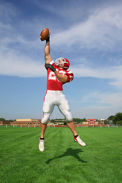 Heavenly Catch Fully extended reciever making fantastic one-handed catch while pointing to the heavens. Almost appears to be giving thanks. wide receiver athlete stock pictures, royalty-free photos & images