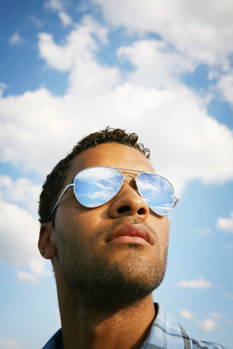 Young guy with mirrored glasses reflecting the blue sky