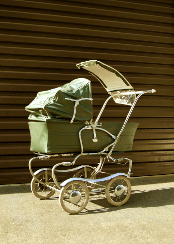 An old baby stroller from the late 1960s/early 1970s in a subtle sepia tone.
