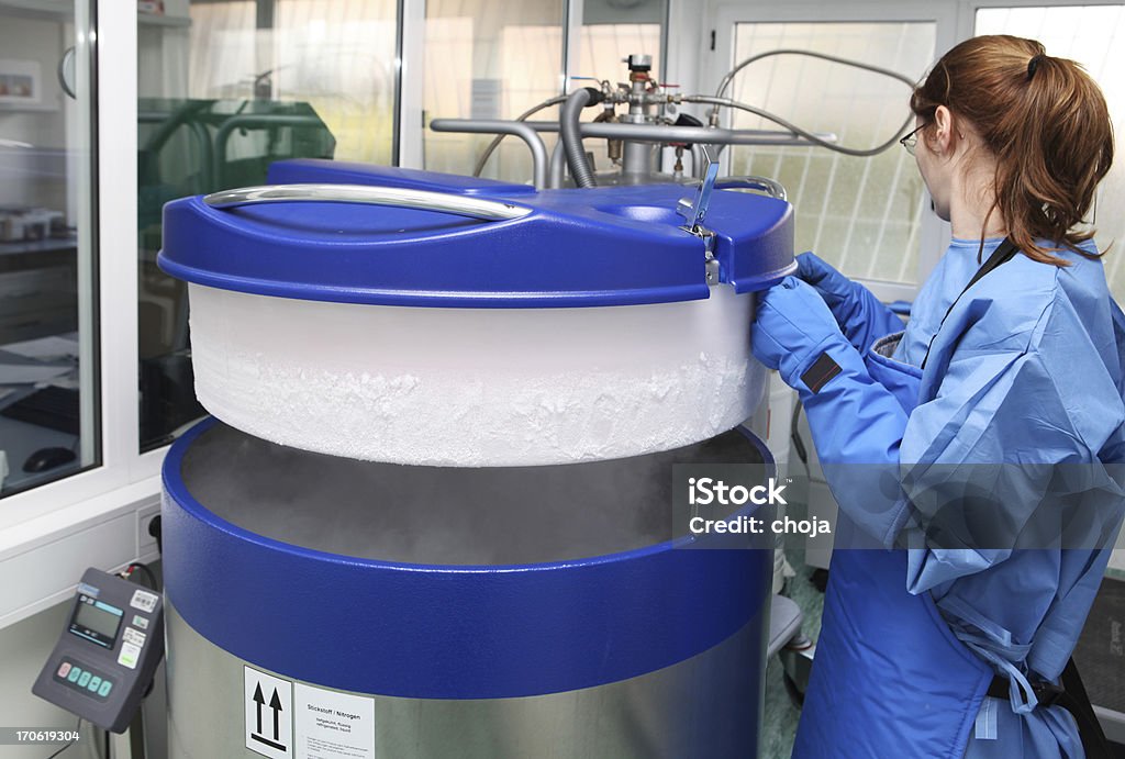 Conteneur avec un liquide nitrogen.doctor en habit de travail - Photo de Cryobiologie libre de droits