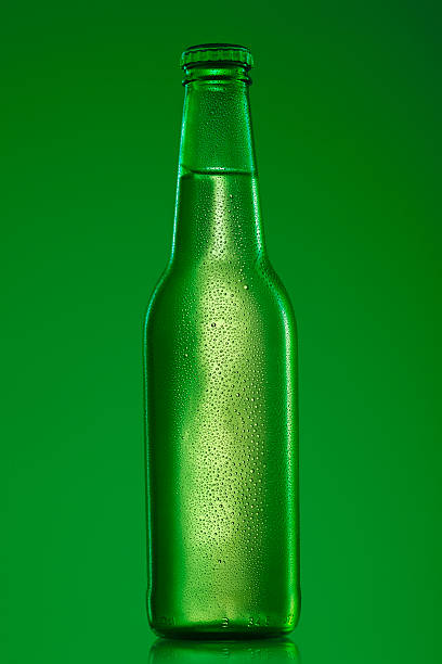 Ice cold bottle of beer Green beer bottle, covered with water drops - condensation, on green background.SEE ALSO: wet bottle stock pictures, royalty-free photos & images
