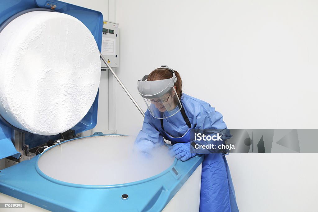 Recipiente com líquidos nitrogen.doctor em traje para operações no trabalho - Foto de stock de Nitrogênio Líquido royalty-free