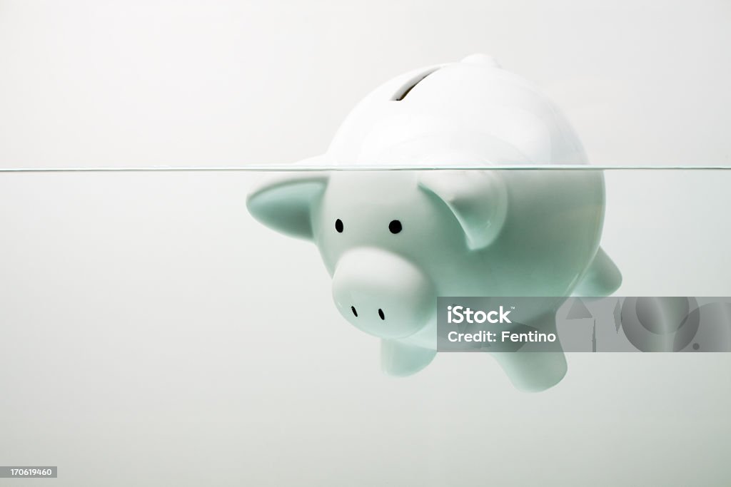 White piggy bank sinking in water Classic white piggy bank floating in water. Bankruptcy Stock Photo