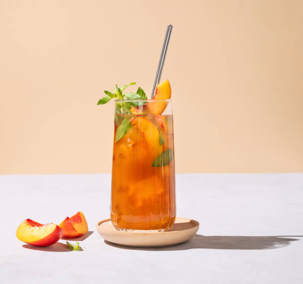 glace aux pêches rafraîchissante et thé à la menthe. boisson estivale froide maison végétalienne sur grand verre sur fond clair avec des fruits frais et des ombres. - georgia peach photos et images de collection