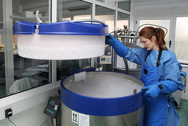 contenitore con il liquido nitrogen.doctor con tuta hazmat al lavoro - cryobiology foto e immagini stock