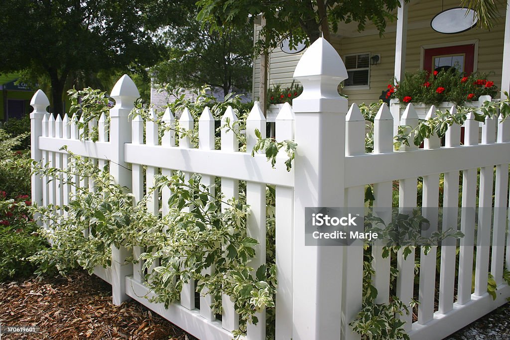 Picket Fence Picket fence with traditional wooden home and geraniums in the background. Rural lifestyle. Fence Stock Photo