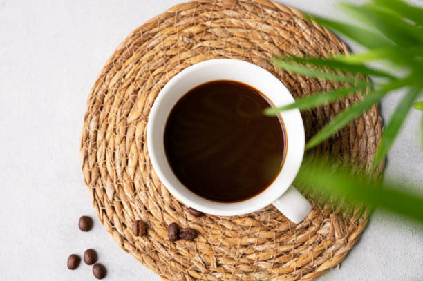 istock A cup of black aromatic coffee on a light background with coffee beans and a palm leaf. Morning energy drink concept. 1706196382