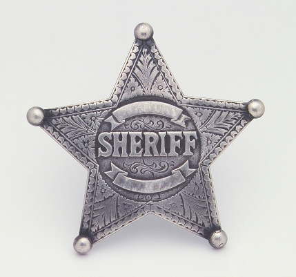 Law and justice in the wild west, American western culture and legal authority concept with picture of metal sheriff badge isolated on white background with clipping path cutout