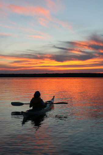 A kayaker watching the sunset on a wilderness lake.