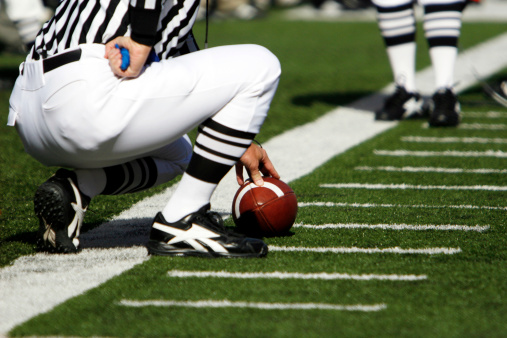 A referee holds a football waiting for the first down measure.