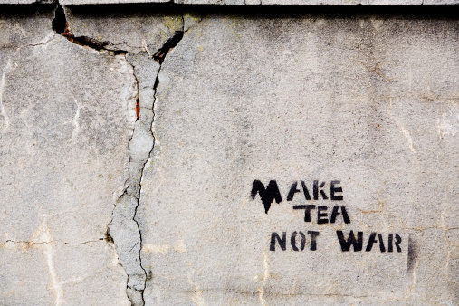 Make Tea Not War -- some humorist's stencilled message on a cracked old wall. The wall is rich in texture, making it useful as a grunge texture or background in its own right. Camera: Canon 5D and L-series lens.