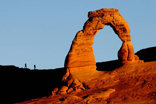 Delicate Arch & Hikers at Sunrise Delicate Arch & Hikers at Sunrise in Arches National Park, Utah. delicate arch stock pictures, royalty-free photos & images