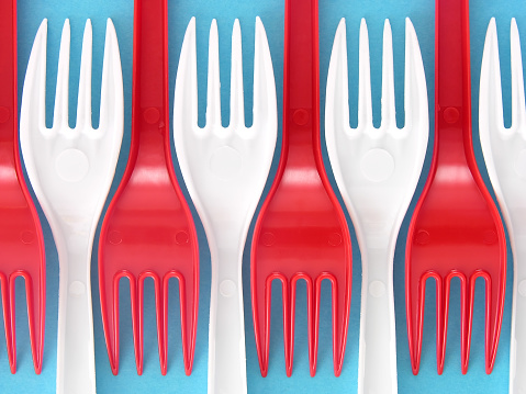 Row of red and white plastic forks over blue textured background