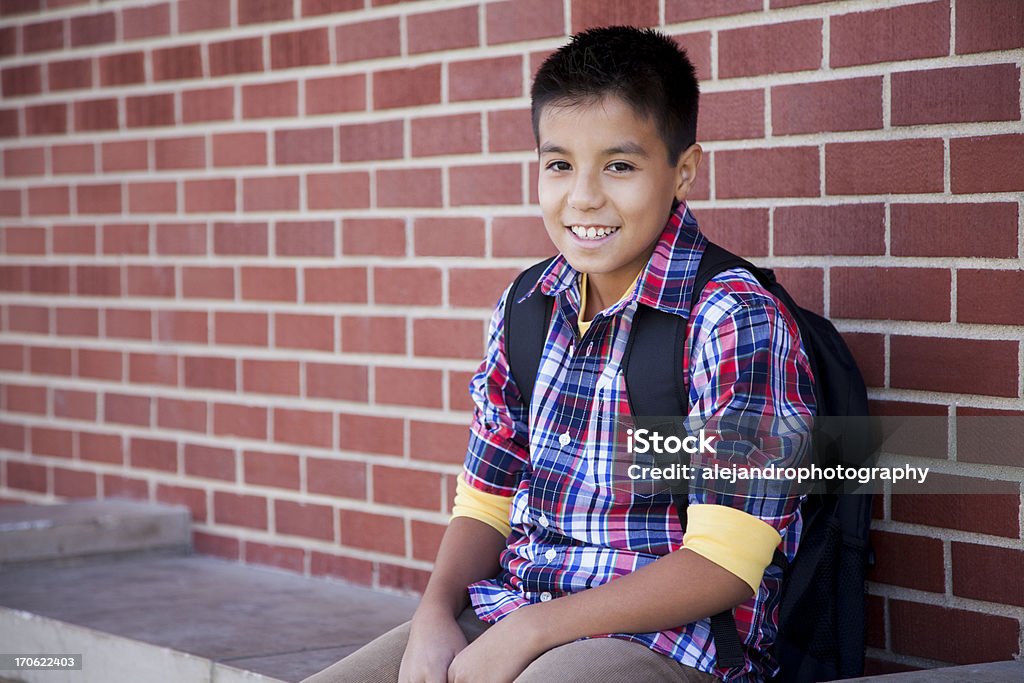 Young student smiling Hispanic elementary student wearing a bookbag carrying books and smiling Book Stock Photo