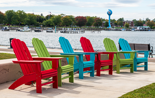 Dunkirk, New York, USA September 27, 2023 Colorful adirondack chairs lined up on the Dunkirk Pier with the city water tower in the background on a sunny fall day