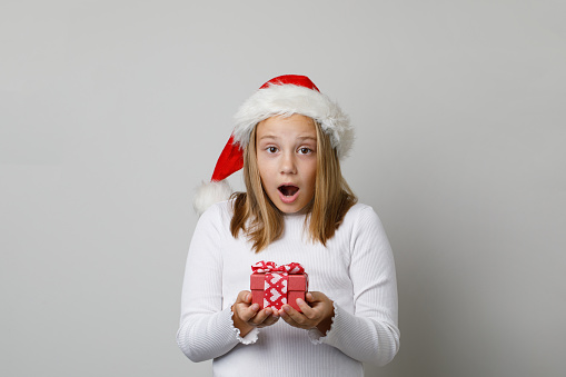Christmas and New Year concept. Happy excited surpeised shocked child girl in Santa hat with open mouth on white background