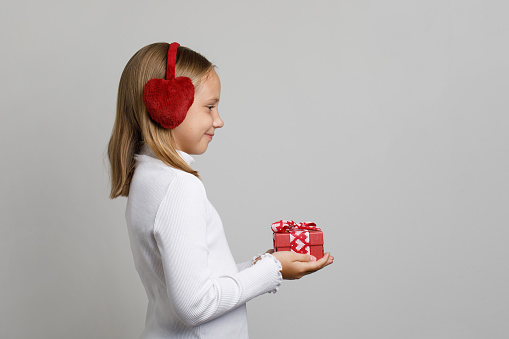 Cute adorable child girl giving red gift present box against white studio wall banner background