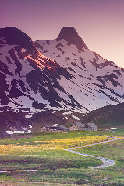 Mountain path leading up to a climbers' mountain retreat at the foot of a snow capped peak. This is just on the border between France, Spain and Andorra. Shot at last light with the warm sunlight just lighting the grass and peaks. Adobe RGB file shot on a Nikon D700