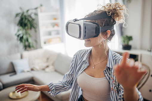 One woman, beautiful young woman having fun with virtual reality headset at home.