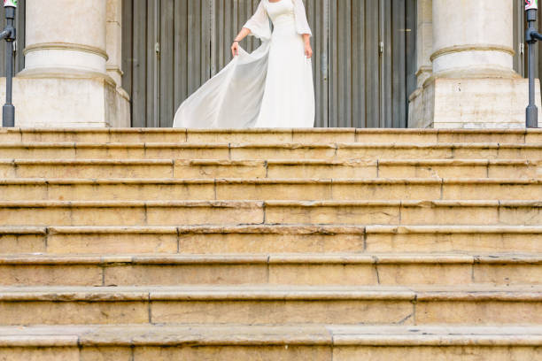 Bride waving her funny wedding dress on a stone stairs.
