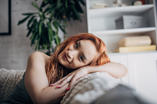 One woman, beautiful redhead woman relaxing on sofa at home.