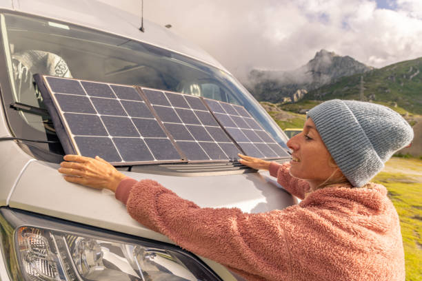 istock Woman camping with her van sets up solar panel on windshield vehicle 1706261720