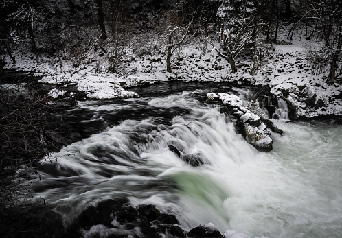 Beautiful green water rapids in the winter, covered in ice and snow.  Long exposure.