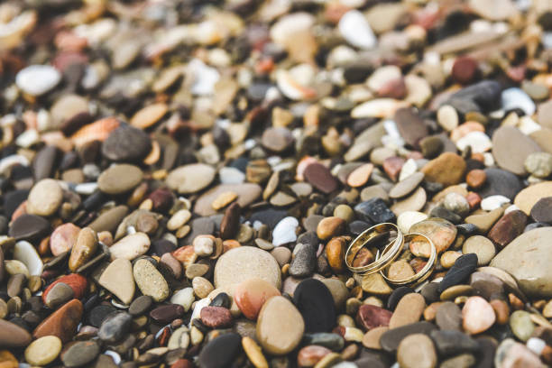 Gold wedding rings on the rocks of a beach.