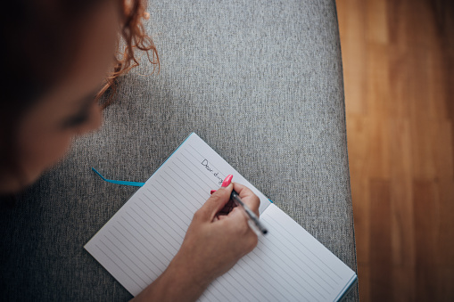 One woman, redhead woman writing a diary and relaxing on sofa at home.