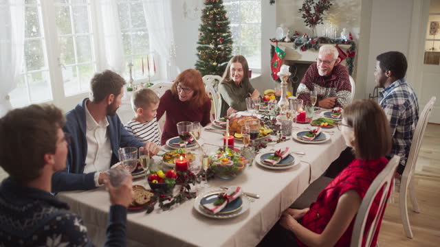 Family, Children, Friends and Young Couples Gather at Home for a Festive Christmas Dinner. Diverse People Enjoy Delicious Turkey Feast and Share Heartwarming Conversations. Cozy Holiday Celebration
