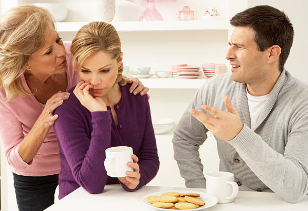 Senior Mother Interfering With Couple Having Argument At Home Senior Mother Interfering With Couple Having Argument At Home Sitting At Table annoying mother in law stock pictures, royalty-free photos & images