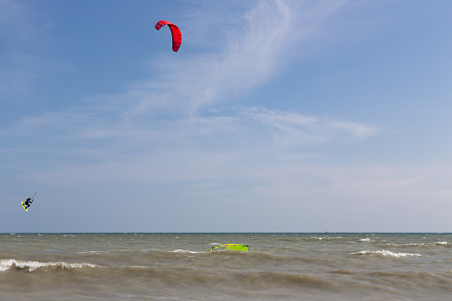Athletic woman having fun while kitesurfing on the sea during summer vacation.
