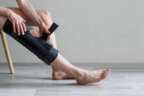 istock Man fixing knee brace while sitting on the chair, rehab 1706279932