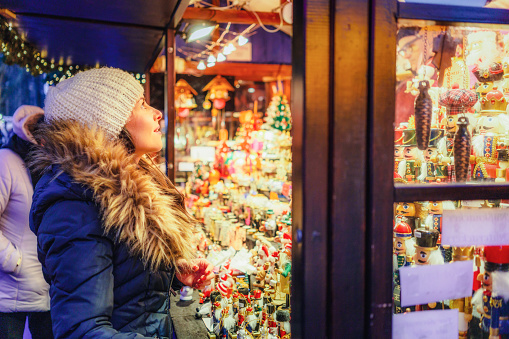 A woman browsing stalls at a winter market for a gift.