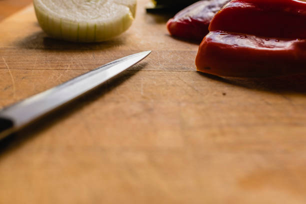 Cooking at home: an anonymous woman slicing peppers and tomatoes for a nutritious vegan lunch.