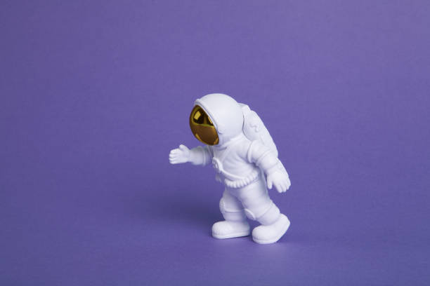 istock an astronaut figurine in a spacesuit exploring a plain purple background 1706322507