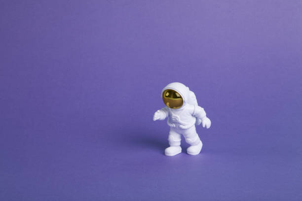 istock an astronaut figurine in a spacesuit exploring a plain purple background 1706322517