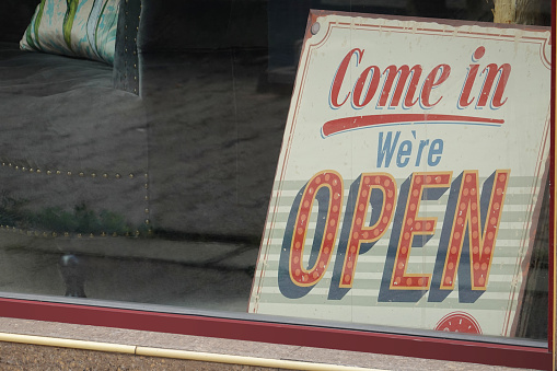 Close up view of a store window with Open sign behind it.