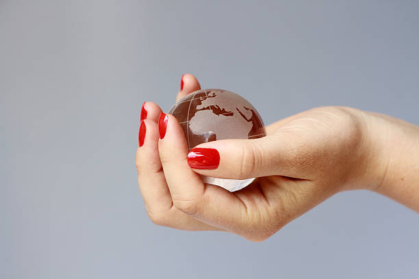 woman's world woman holding glass globe, concept world in woman's hand red nail polish stock pictures, royalty-free photos & images