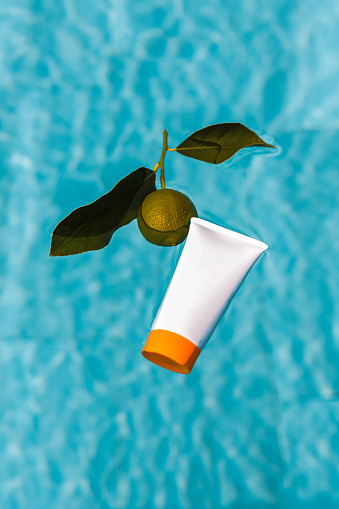 Beauty Product Tube Packaging floating on swimming pool water surface with lime fruit