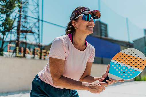 Mature woman playing beach tennis at court