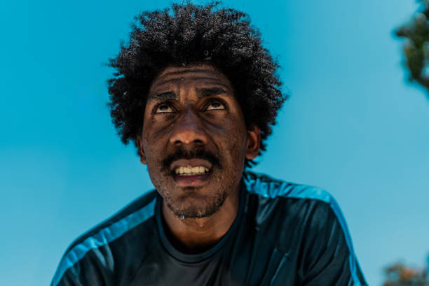 africa village, single african man headshot, in the township , tough manly look, standing outdoors in the yard in front of the house door