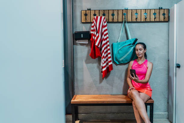istock Mature woman using mobile phone on locker room at gym 1706403664