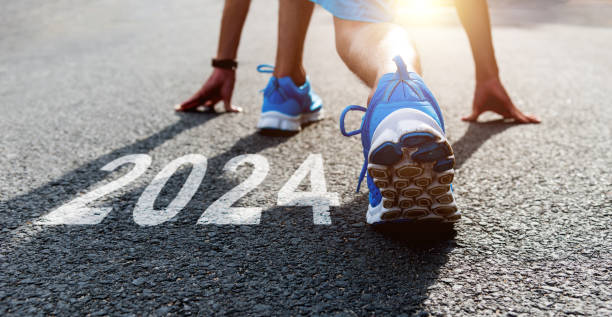 joven deportista preparándose para correr con el número de año nuevo 2024 en carretera asfaltada - prepared sole fotografías e imágenes de stock