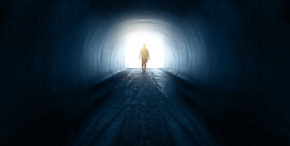 Rear view of boy walking at the end of the tunnel