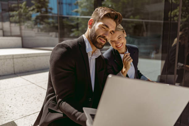 istock Two business colleagues working on project while sitting outdoors on modern building background 1706417414
