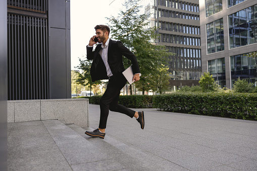 Businessman run and hurry up to office while talking phone with customers. High quality photo